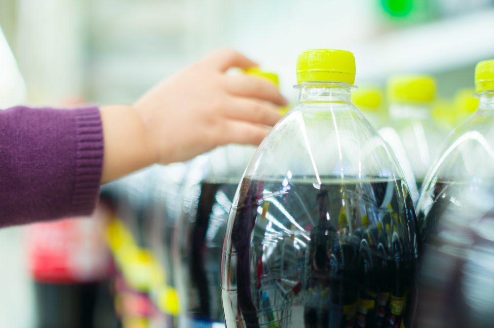 female arm reaches for soda bottle in store