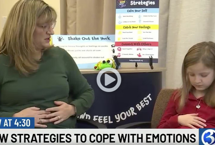 A woman sits next to a child in front of Feel You Best Self Materials. They both have two hands on their abdomens. Underneath the picture are the words 